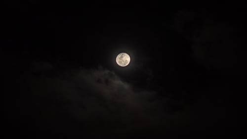 Glowing Full Moon Behind Fast Moving Clouds at Night