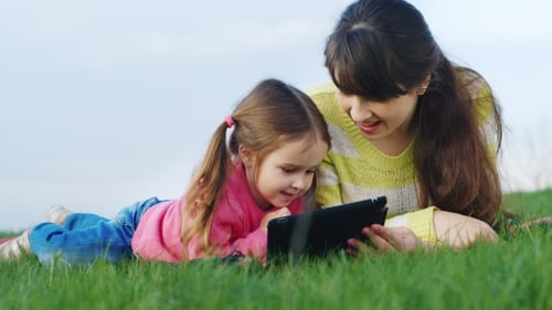 Mother and Child Relaxing Outdoors with Tablet
