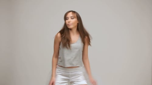 Brunette Woman Dancing in Gray Top and White Shorts