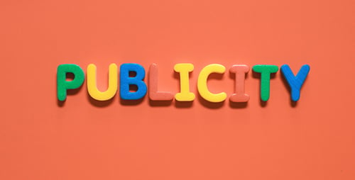 Hands Forming Publicity Letters on Orange Background