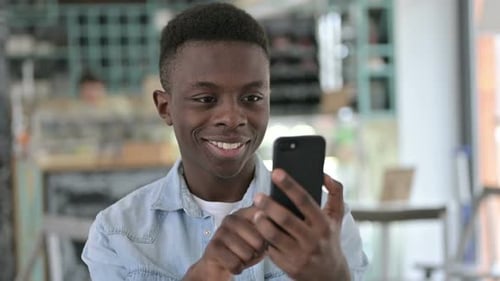 Young Adult Smiling While Using Smartphone Indoors