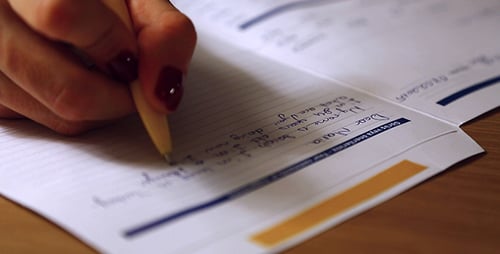 Hand Writes Letter in Notebook with Wooden Pen