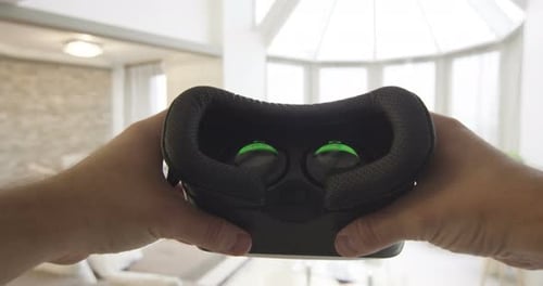 Hands Holding Virtual Reality Headset in Modern Home
