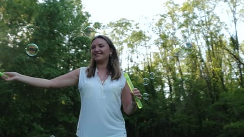 Woman Blowing Bubbles in a Green Park