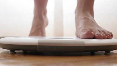 Female measuring weight on health scale close-up 4K 2160p 30fps UltraHD footage - Woman legs approac