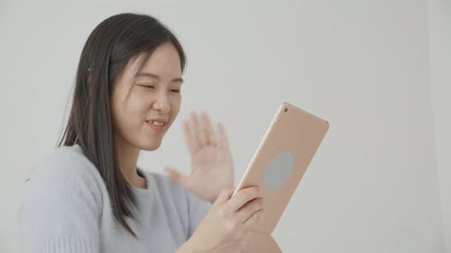 Young asian woman using digital tablet computer for video conference online with friends.