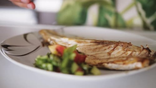 Close Up View of Hand Squeezing Lemon on Baked Sea Bass Fillet