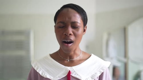 Vue de face : Jeune femme afro-américaine mince bâillant au Ralenti en regardant la caméra