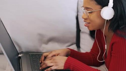 Woman Uses Laptop with Headphones Indoors
