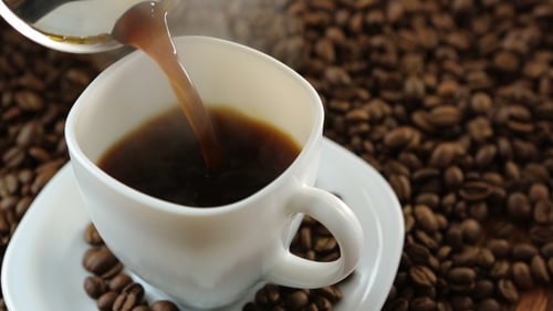 Pouring hot coffee into white cup