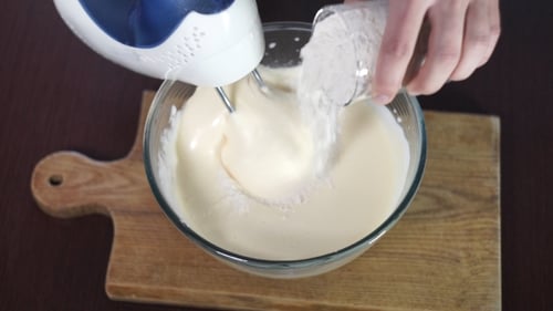 Electric Mixer Combining Flour and Batter in Bowl
