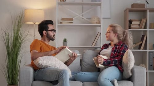 Friends Discussing Books on a Comfortable Sofa