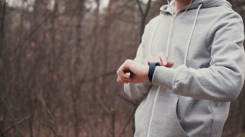 Man Running In Forest Woods Training And Look At Smart Watches.