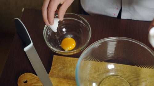 Cook Separating Egg Yolk in Glass Bowl