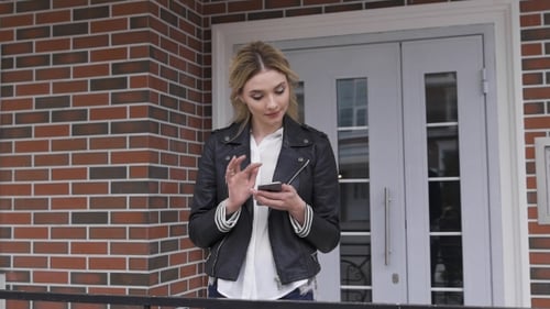 City Lifestyle Stylish Girl Using a Phone Texting On Smartphone App In a Street