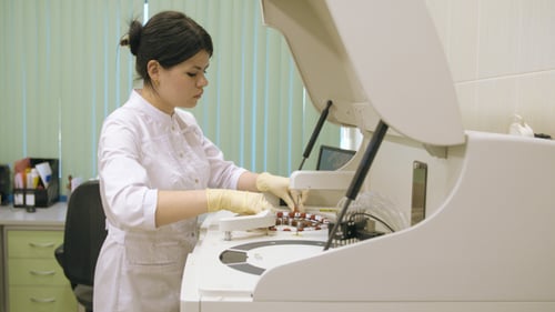 Woman Loads Blood Samples into Automated Analyzer