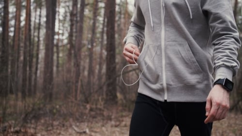 Man Checks Phone While Running in Forest