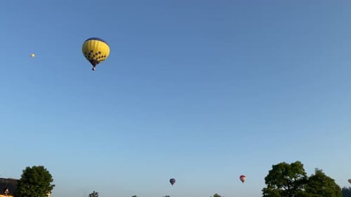 Colorful hot air balloons fly in the sunny morning over green park. Maneuverable flight. Travel,
