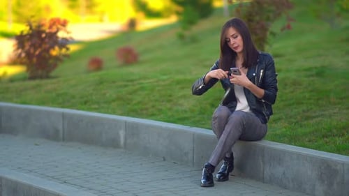 Attractive Girl in the Park Paints Her Lips