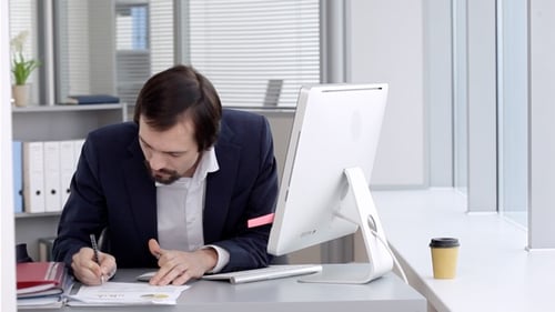 Businessman Writing, Typing at Computer in Modern Office