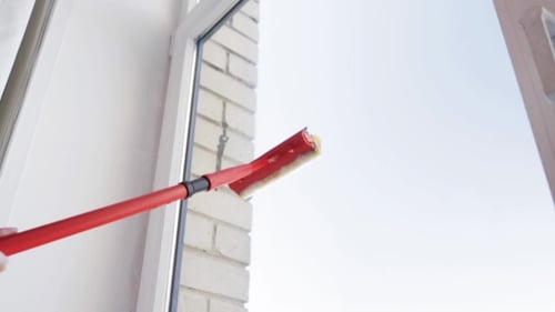 Person Washing a Window with Cleaning Tool