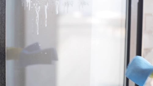 Woman Cleaning Glass Window With Rag and Cleaner