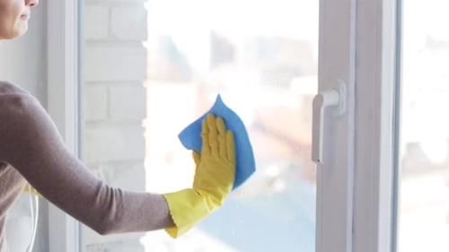 Frau in Handschuhen Fenster putzen mit Lappen 15