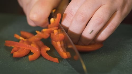 Woman Slices Red Pepper into Strips on Board