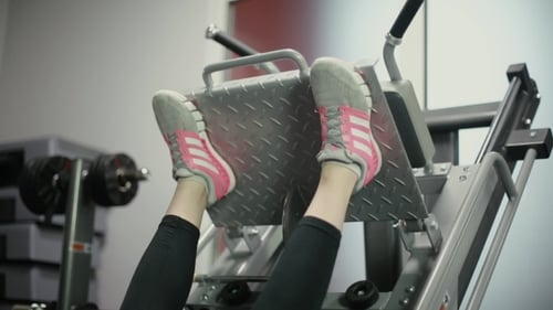 Woman Exercising Legs on Leg Press Machine