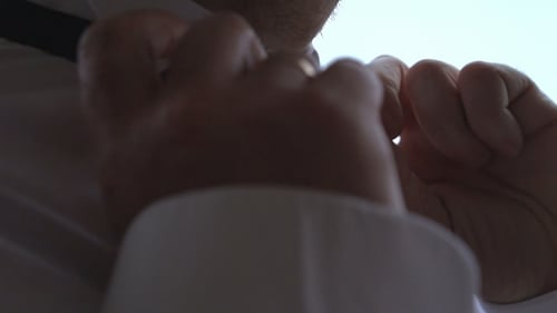 Man Adjusting Spotted Bow Tie on White Shirt
