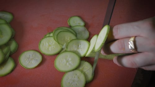 Slicing Fresh Green Zucchini on Cutting Board