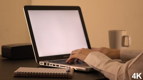 Woman Types at Laptop with Blank White Screen