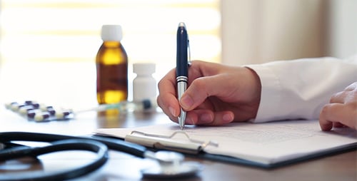 Healthcare Professional Writing Prescription on Desk