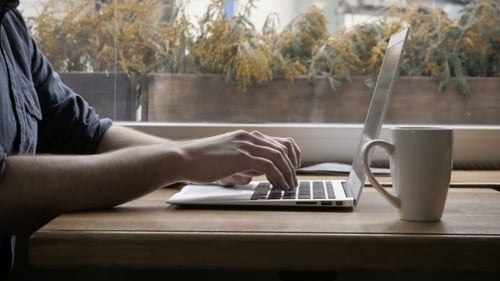 Lächelnder Gelegenheitsstudent arbeitet am Laptop im Café