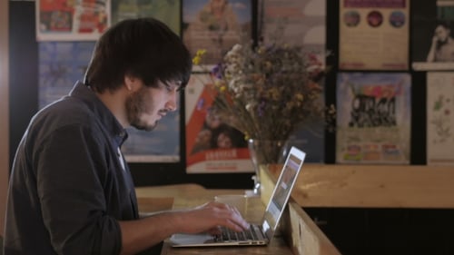 Lächelnder Gelegenheitsstudent arbeitet am Laptop im Café