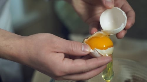 Cracking Egg Close-Up with Bright Yolk