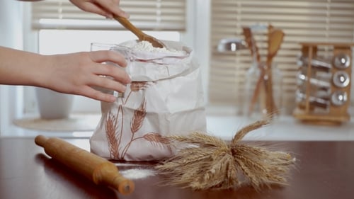 Hands Scooping Flour into Glass in Kitchen