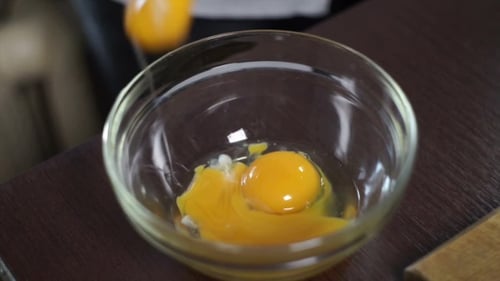 Baking Ingredients, Fresh Organic Eggs Falling Into a Deep Glass Bowl For Mixing