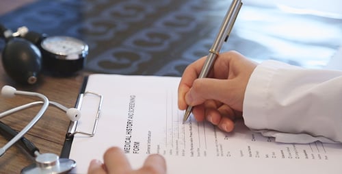 Hand Filling out a Medical Form in Doctor's Office