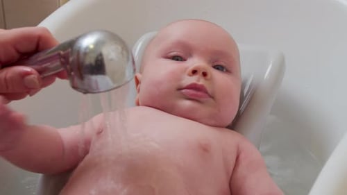 Newborn Infant Lies In Tub Getting Washed