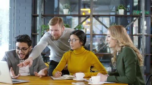 Happy Colleagues Reading News on Laptop and Giving High Five in Cafe