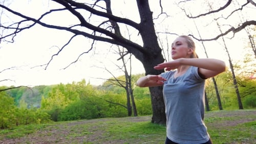 Woman Exercises in a Spring Park at Sunrise