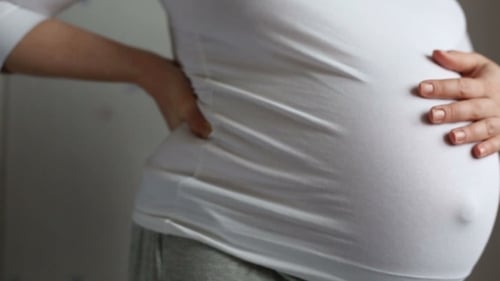 Pregnant Woman Holding Belly and Lower Back