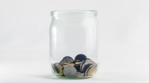 Filling Glass Jar with Coins for Savings