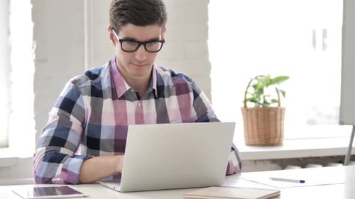 Young Adult Typing on Laptop at Bright Desk