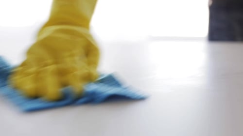 Gloved Hand Cleaning a White Surface