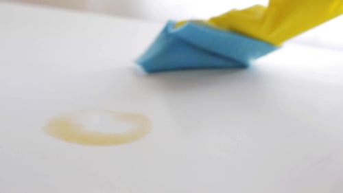 Hand Cleaning White Surface with a Blue Cloth