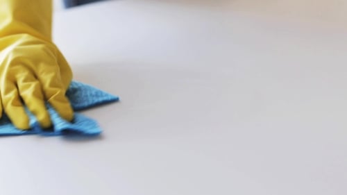 Hand Wiping White Surface with Blue Cloth