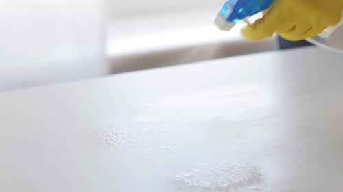 Person Cleaning a White Surface with Spray and Cloth