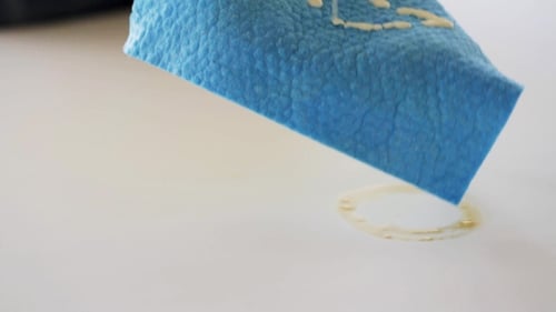 Gloved Hand Cleaning a White Surface with Cloth